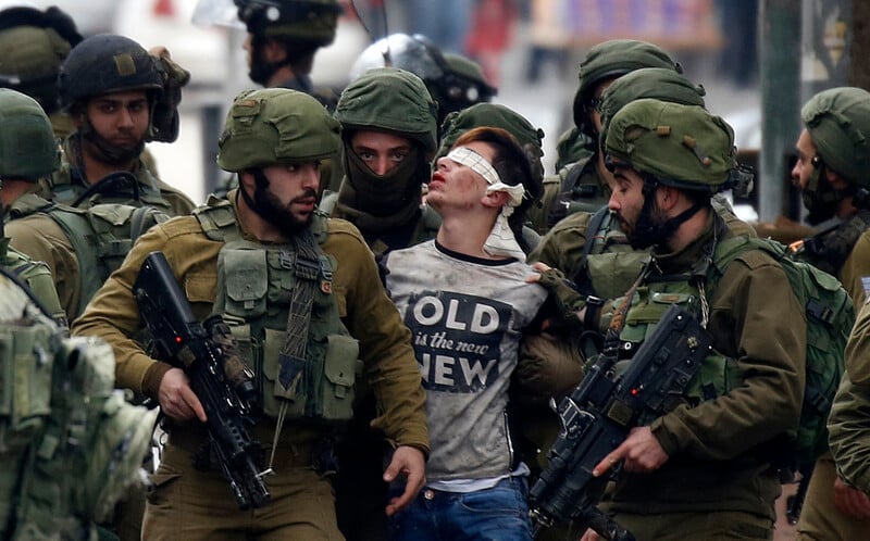 Soldiers arrest a blindfolded boy