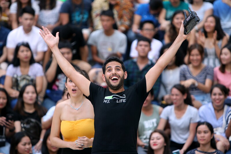 Man stands before crowd with arms wide open 