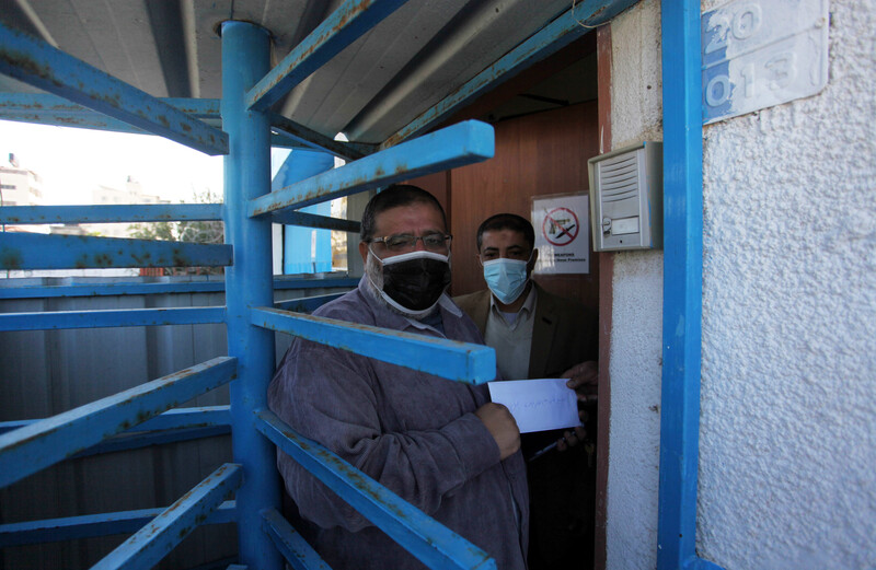 A man stands in a metal swing door carrying a piece of paper