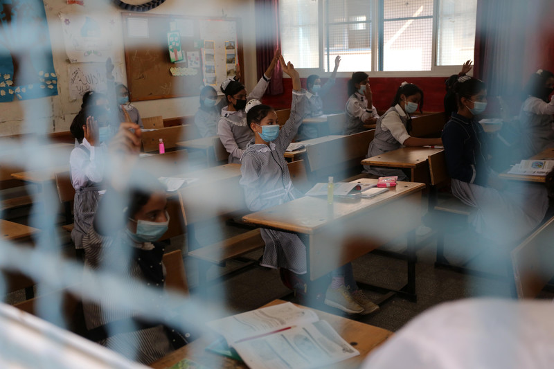 Schoolchildren are seen in their classroom through a wire mesh