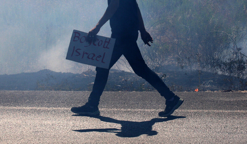 Neck-down silhouette of a person walking with a sign