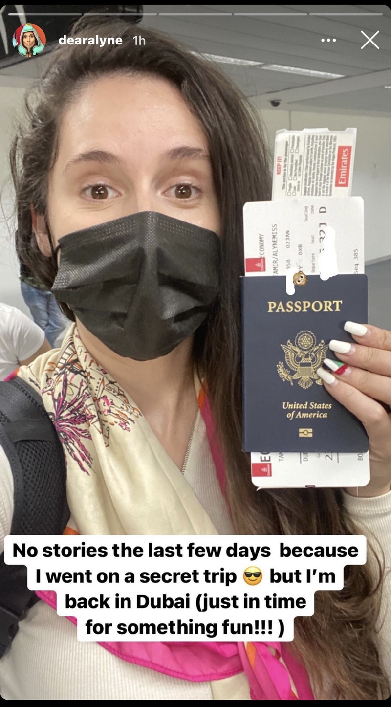 A woman holding a passport, wearing protective mask 