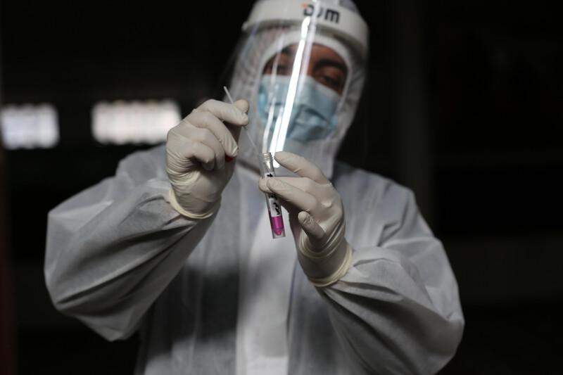 Man wearing protective gear places swab in test tube