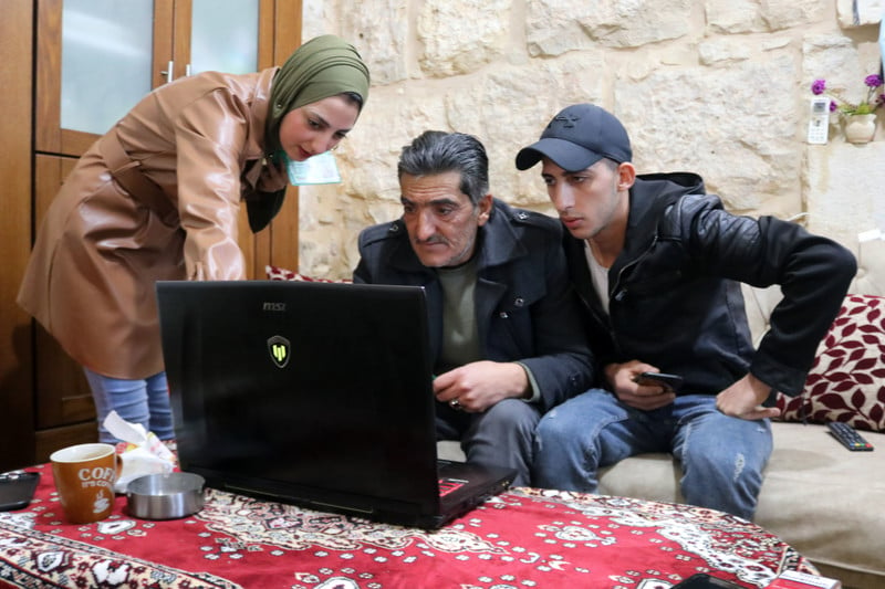 Two men and a woman stare at a laptop