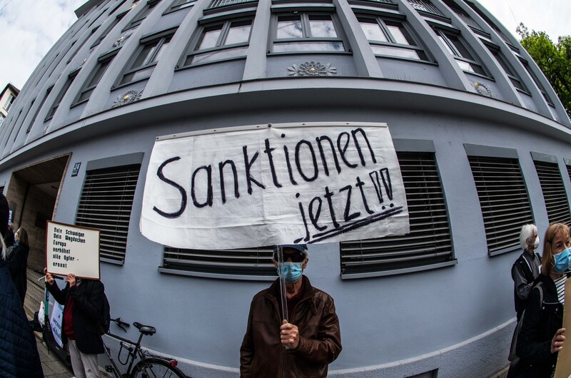 A man in face mask holds up a sign in German