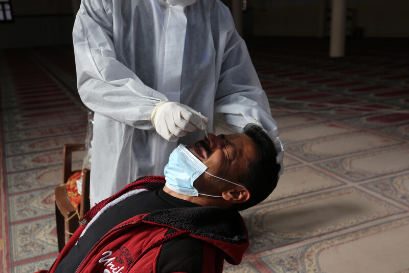 A man flinches as a medical worker in full protective gear swabs his nose