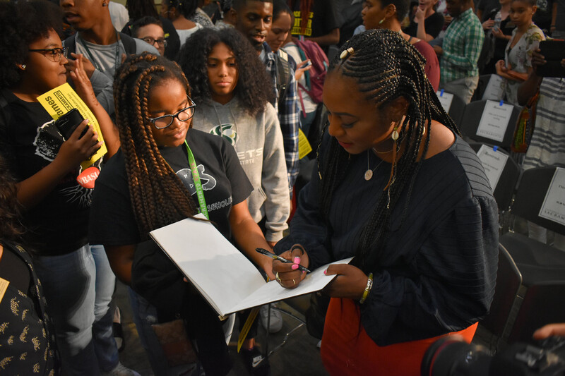 Woman signs book with onlookers