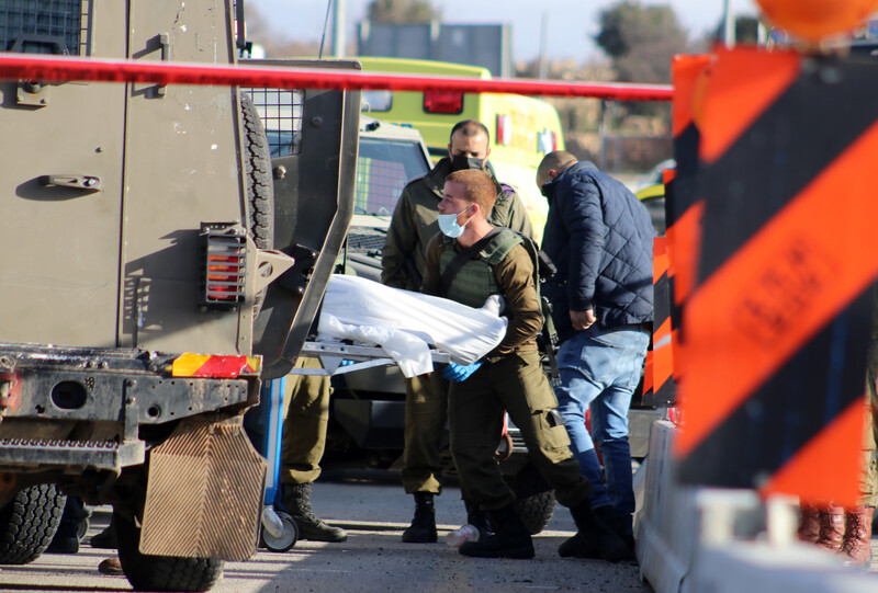 A soldier loads a corpse on a stretcher in the back of a military vehicle 