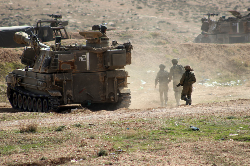 Soldiers walk near military tank 