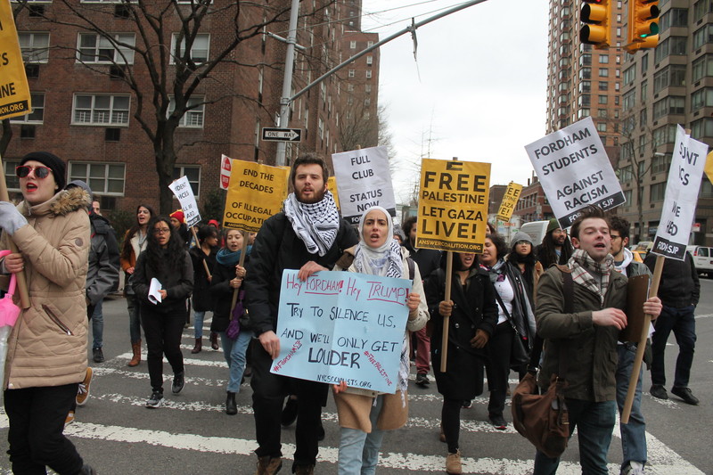 Demonstrators hold signs protesting Fordham's ban of SJP