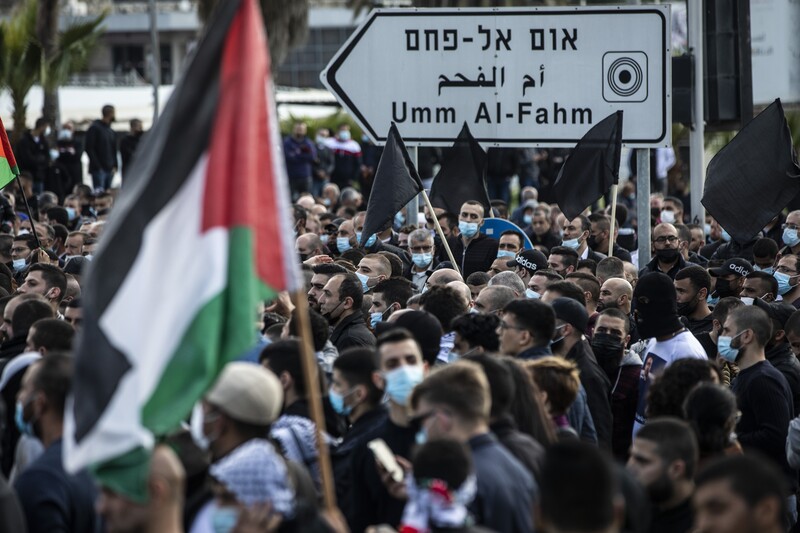 People demonstrate in large numbers, holding flags  