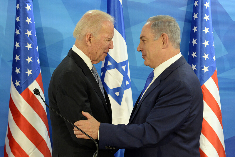 Two men embrace in front of US and Israeli flags