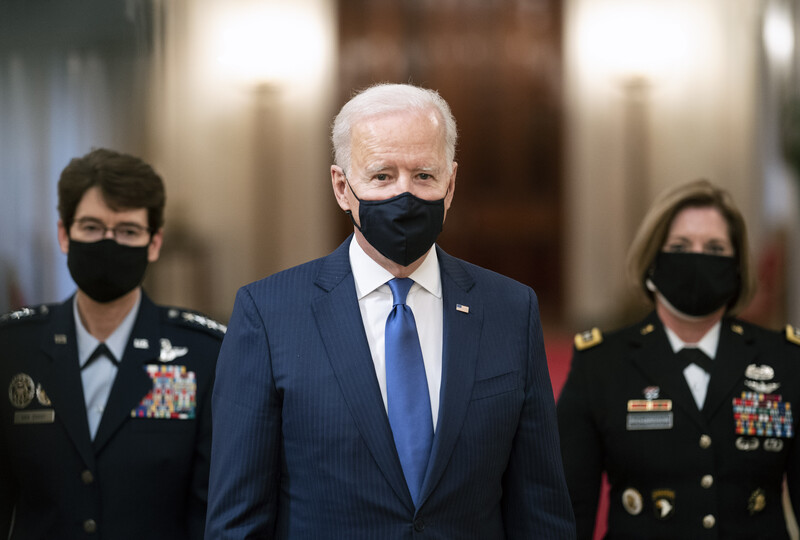 Man in suit flanked by generals