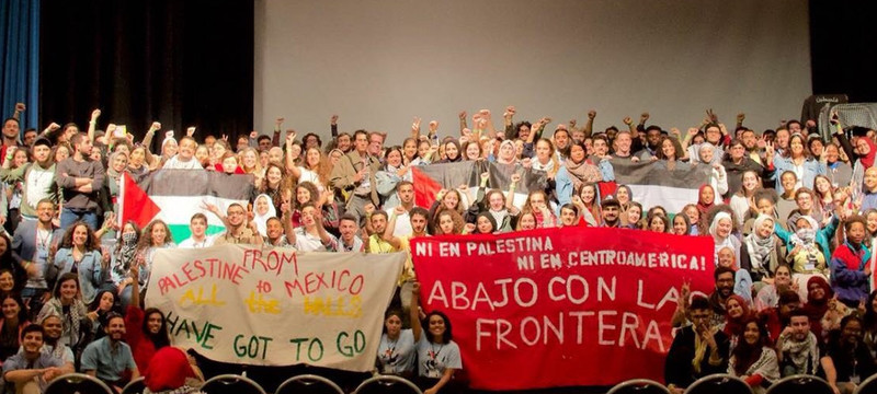 Activists gather on a stage and hold banners