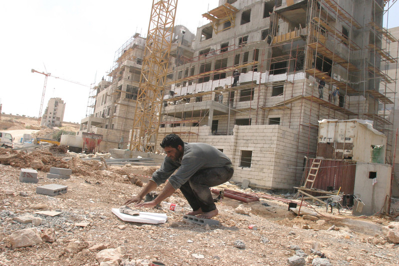 A man crouches near a construction site