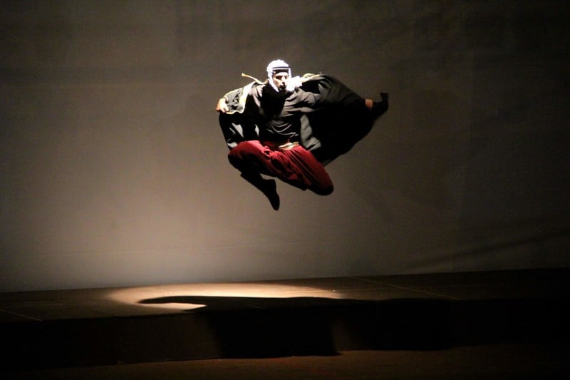 A man in traditional Palestinian black and white headgear flies through the air