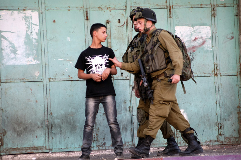 Two soldiers grab a boy's arm