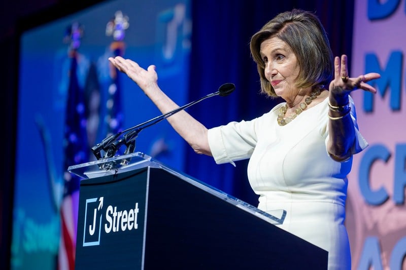 A woman stands at podium with arms outstreched