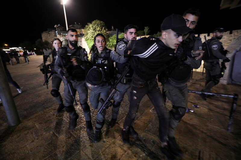 Men and women in uniform restrain a young man