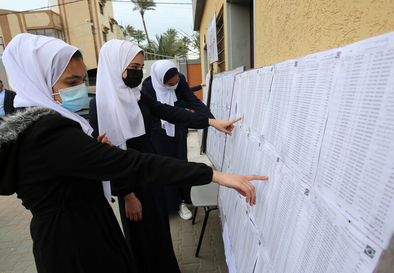 Women point to sheets of paper hung on notice boards