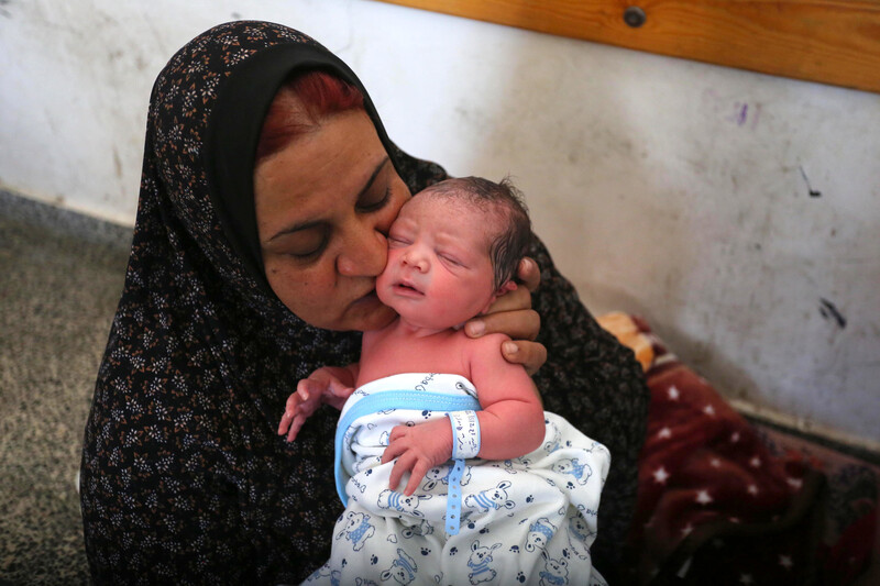 Woman kisses newborn baby while sitting on floor
