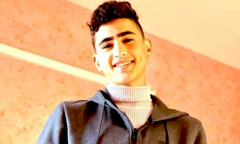 A boy is smiling, wearing a turtle neck and a hoodie 