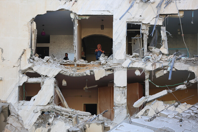 Women stand inside destroyed building 