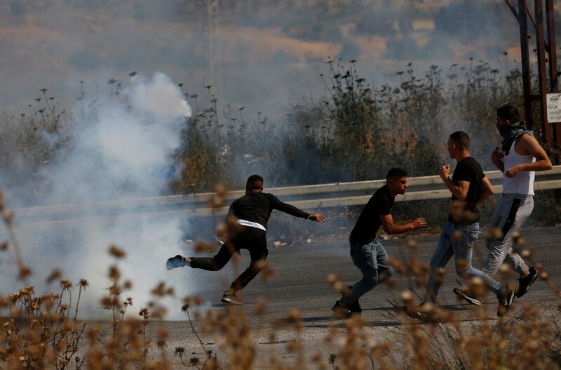 Men run away from cloud of tear gas smoke 