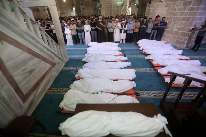 People pray at the mosque over 17 bodies wrapped in white cloth 