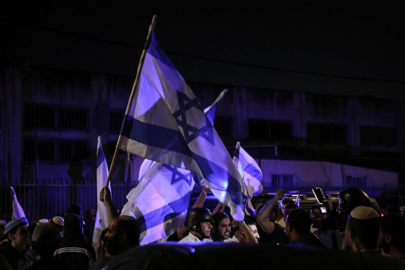 Protesters wave Israeli flags during the night