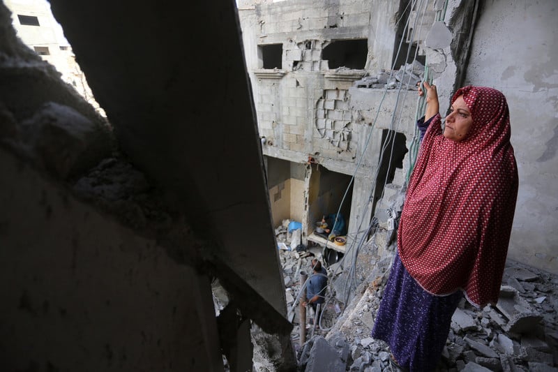 Woman stands in bombed-out apartment building