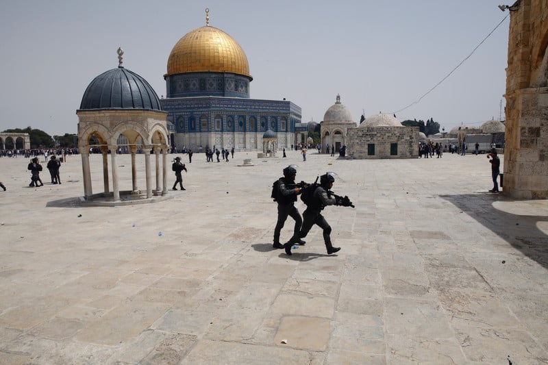 Fully armed soldiers take position, Dome of the Rock in the background 