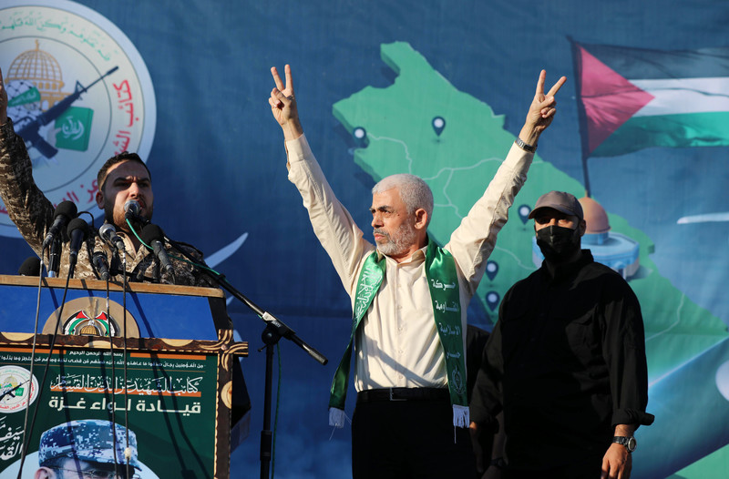 Yahya Sinwar raises arms in air and makes V for victory hand gesture while standing on stage