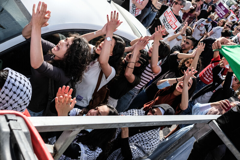 A crowd of people demonstrating with chants and signs and flags