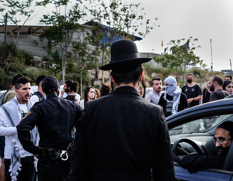 A man argues with a policeman as onlookers stand around