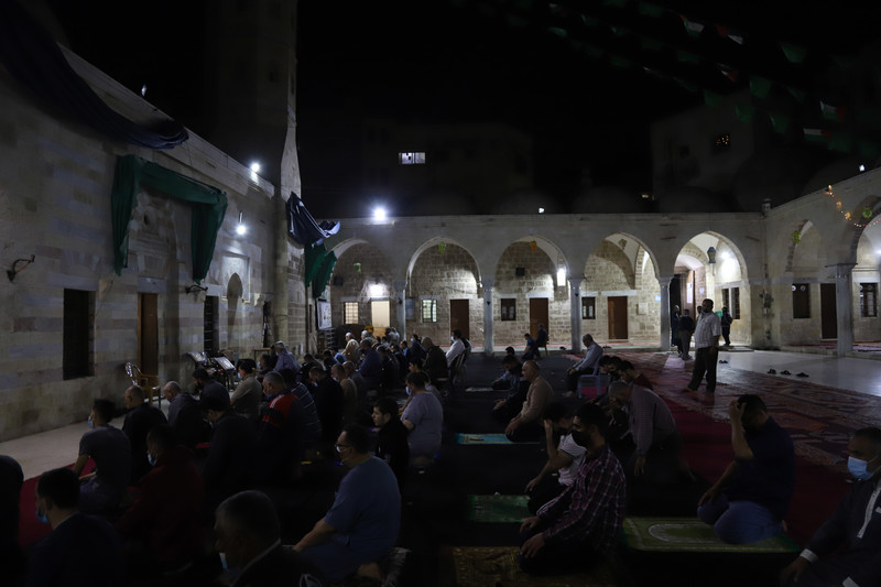 Men pray in the dark in an outdoor mosque courtyard