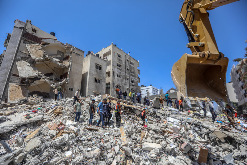 People walk over rubble of destroyed buildings 