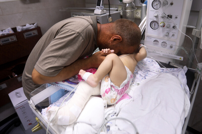 Man leans over and embraces child on a hospital bed