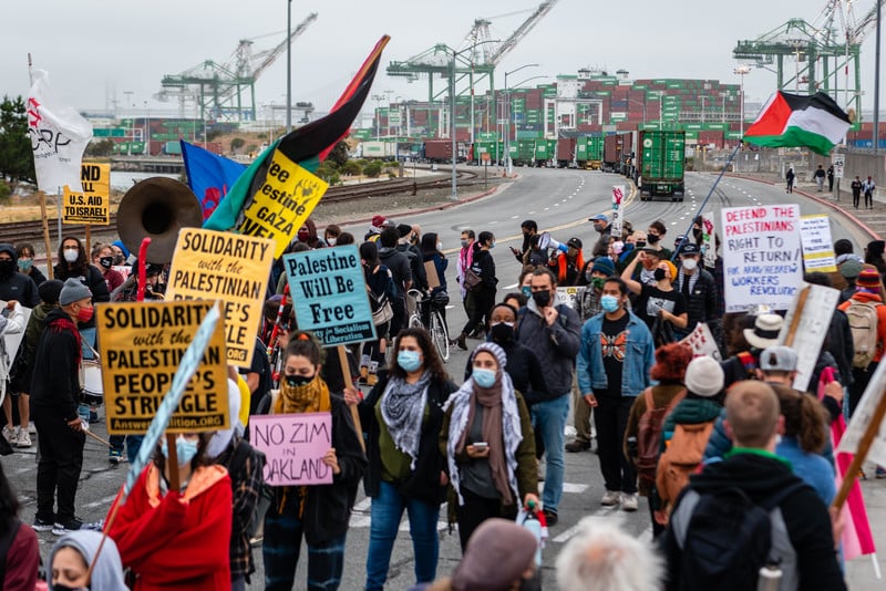 Protesters hold signs in front of cargo ships