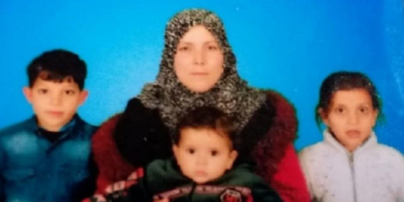 Woman holding a toddler, surrounded by two other children 