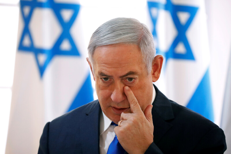 Benjamin Netanyahu touches a finger to his face