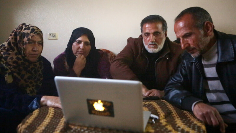 Four people sit in front of laptop