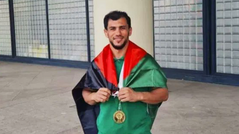 The Palestinian flag is draped around the shoulders of a smiling man