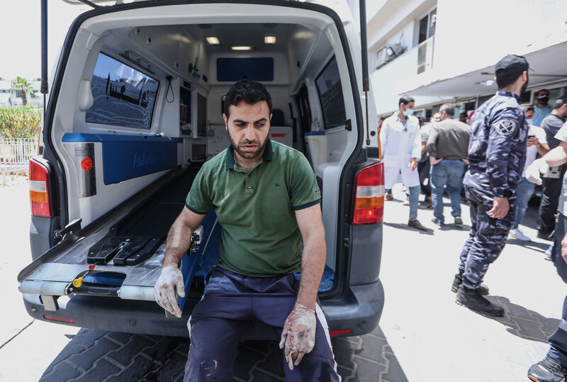A man rests by the open back of an ambulance
