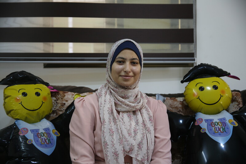 A woman poses with two balloon graduates