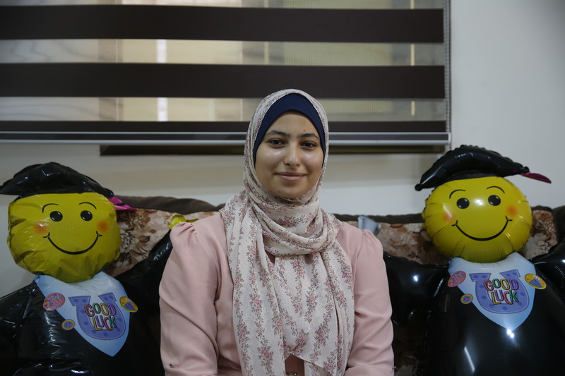 A woman poses with two balloon graduates