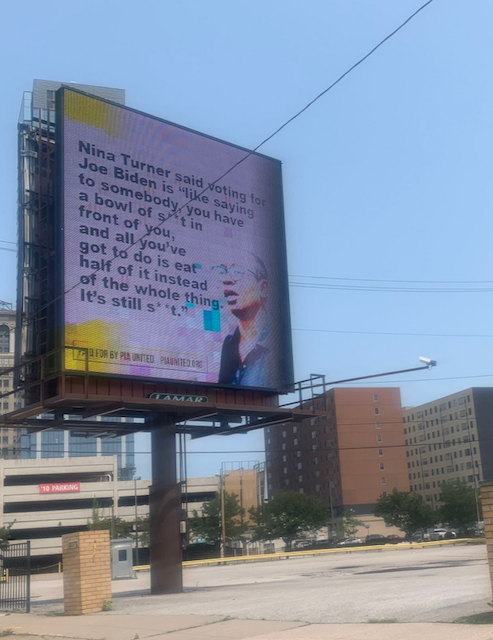 Photo of large ad sign with buildings in background