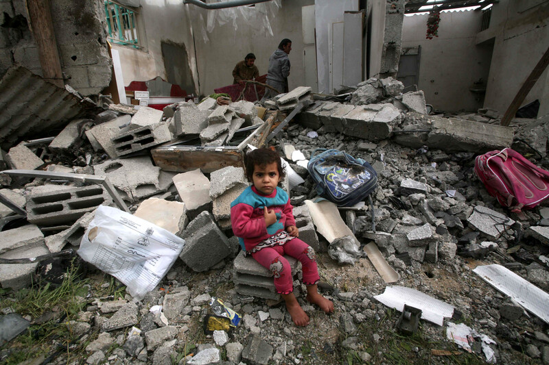 A young child sits in rubble