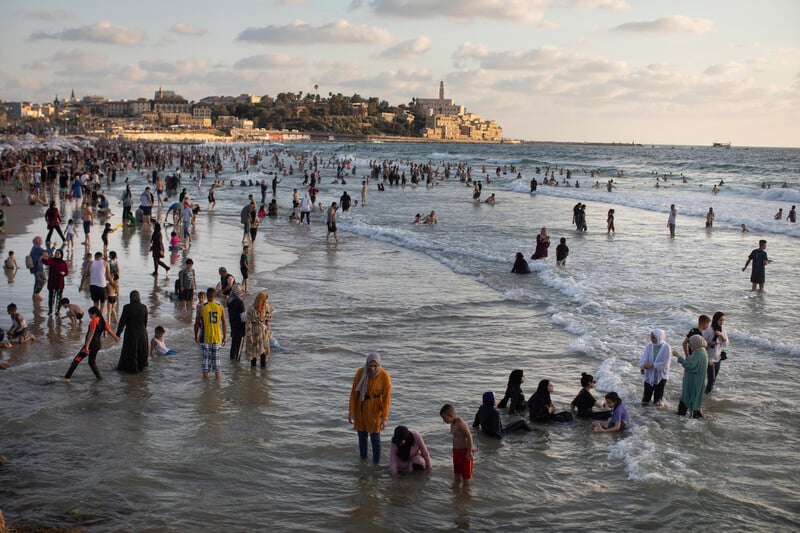 Women and children play on a beach in the sea