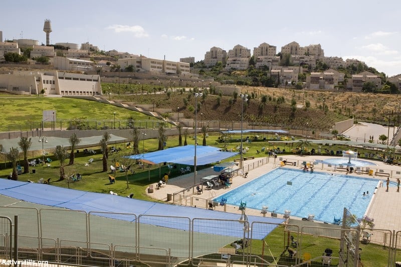 Landscape view of swimming pool in green hillside with settlement in background